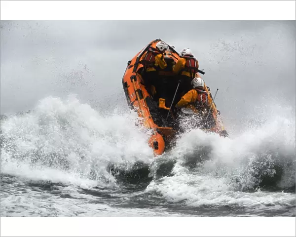 St Agnes D-class inshore lifeboat Blue Peter IV D-641 heading through a breaing wave. Crew members Gavin Purcell, Gavin forehead and Richard Llewellyn on board