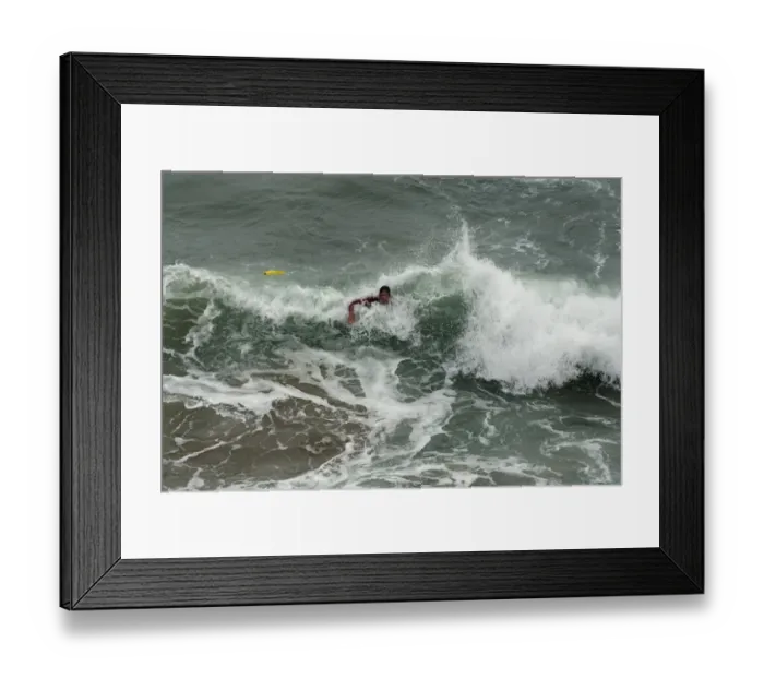 Framed Print : An RNLI lifeguard swimming through heavy surf at Perranporth Framed Print : An RNLI lifeguard swimming through heavy surf at Perranporth