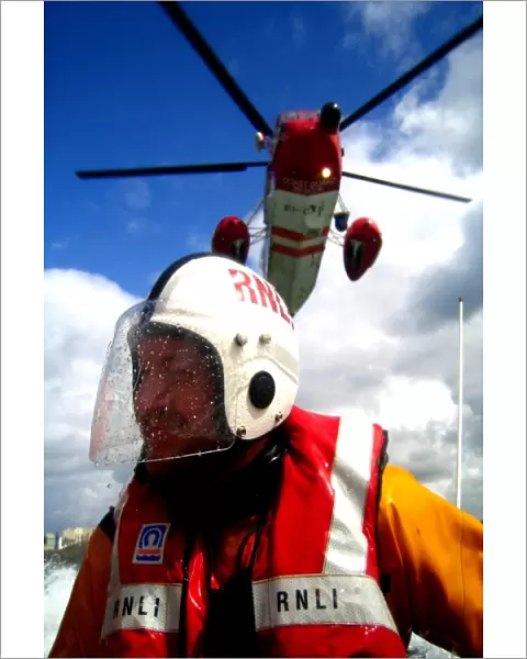 Portrait shot of a coastguard helicopter above an RNLI ILB crew