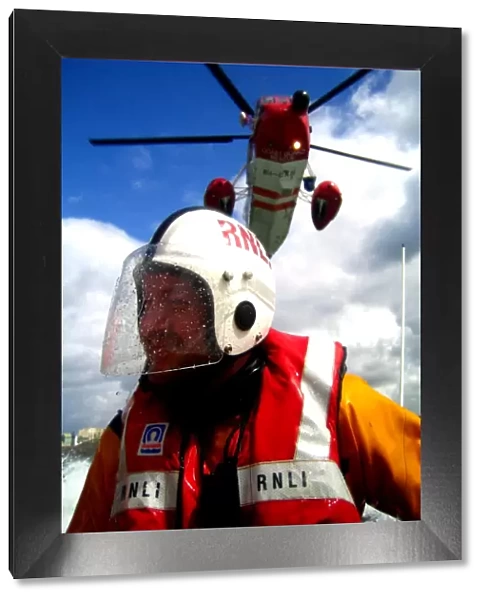 Portrait shot of a coastguard helicopter above an RNLI ILB crew