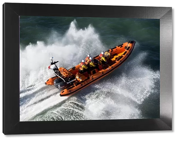 Newquay Atlantic 85 class inshore lifeboat The Gladys Mildred B-821. Lifeboat heading left to right, four crew on board, lots of white spray