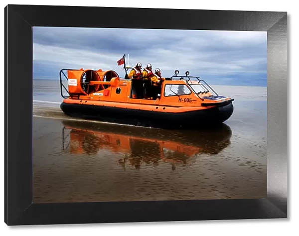 New Brighton hovercraft Hurley Spirit H-005 during a training exercise on mudflats. Four crew in view, hovercraft moving from left to right