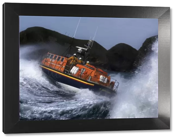 St Davids Tyne class lifeboat Garside 47-026 in rough seas. Three crew can be seen at the upper steering position. Lifeboat is breaking through a large wave and lots of white water
