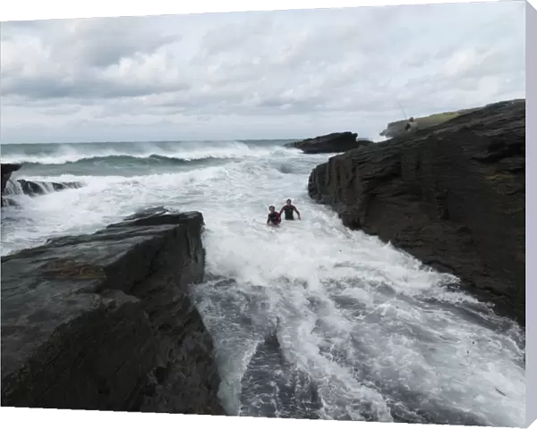Reconstruction of the rescue of a fisherman by two RNLI lifeguards Chris Boundy and John Dugard at Trebarwith Strand, Cornwall. Picture shows the two lifeguards struggling through surf in the area called the Washing Machine, fisherman on rocks