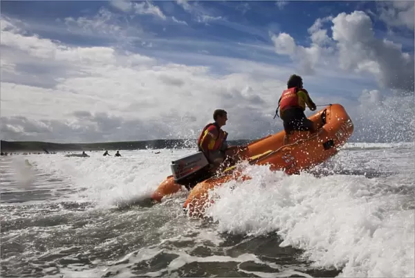 Two RNLI lifeguards in the surf at Woolacombe beach, Devon on an arancia inshore rescue boat