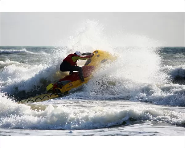 Lifeguards on Boscombe beach, Dorset. Lifeguards are now providing year round cover at Boscombe due to the development of the surf reef. Lifeguard on a rescue watercraft moving from left to right through a breaking wave