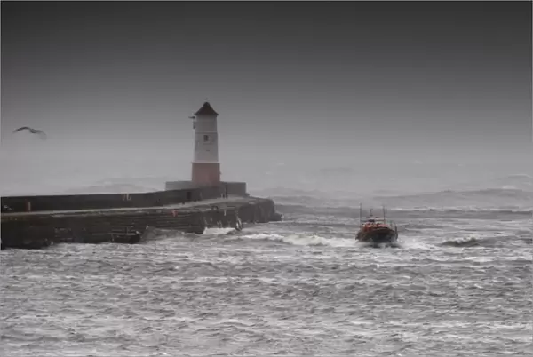 Berwick upon Tweed Mersey class lifeboat Joy and Charles Beeby 12-32 heading toward the camera in rough seas. Harbour wall and lighthouse to the left of the photo
