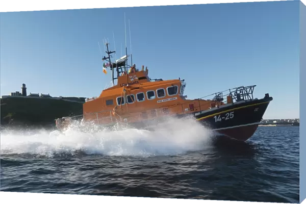 Ballycotton Trent Class lifeboat Austin Lidbury 14-25 moving from left to right, lighthouse in the background. Bright sunny day, blue sky