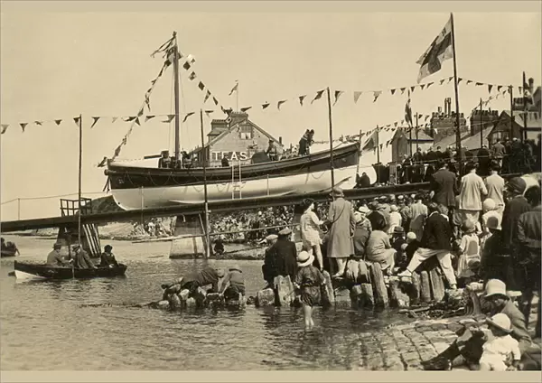 Swanage motor lifeboat Thomas Markby being launched down the slipway, crowds of people gathered on the shore. Black and white photo taken in 1928
