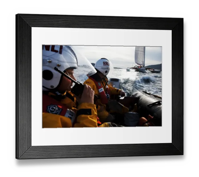 Framed Print : Two crew members from Barra RNLI on an ILB in the foreground, one talking into a radio. Yacht competing in the Round Britain and Ireland yacht race 2010 in the background. Leisure Framed Print : Two crew members from Barra RNLI on an ILB in the foreground, one talking into a radio. Yacht competing in the Round Britain and Ireland yacht race 2010 in the background. Leisure