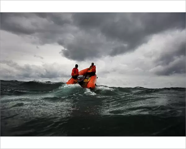 Two lifeguards on an arancia inshore rescue boat at Watergate Bay, Cornwall, headingaway from the camera
