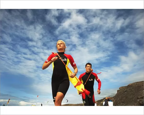 Two lifeguards running along the beach towards the camera, taken from below looking up
