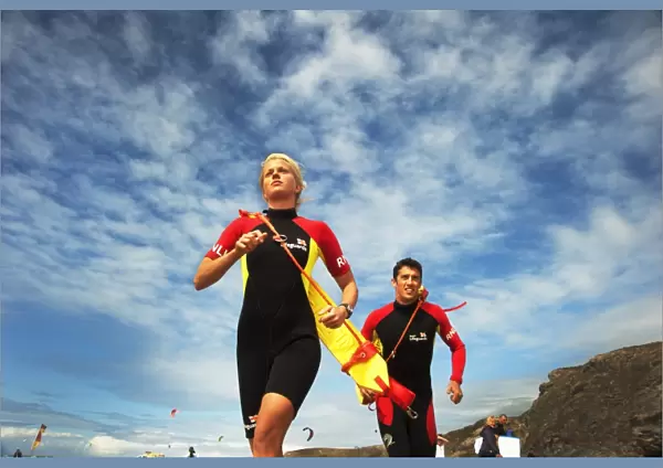 Two lifeguards running along the beach towards the camera, taken from below looking up