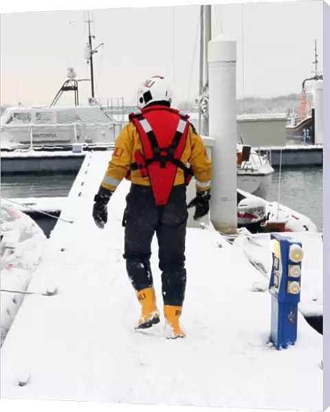 Lifeboat crew member walking along a snow covered pontoon at the Lifeboat College, Poole