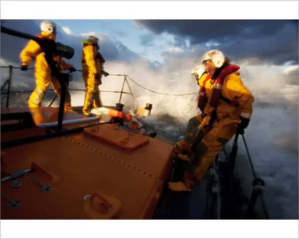 Crew members stood at the bow of the Berwick-upon-Tweed Mersey class lifeboat Joy and Charles Beeby 12-32, lots of spray