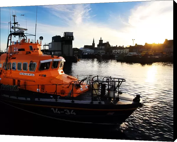 Fraserburgh Trent class lifeboat Willie and Mary Gall 14-34 in the harbour, sun low behind buildings in the background