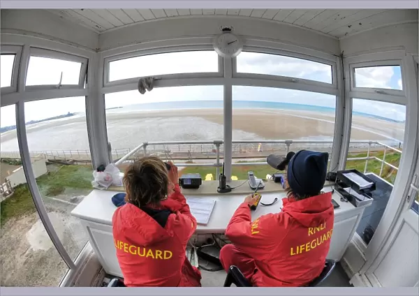 Two lifeguards monitoring the sea at a beach in Jersey from lifeguard hut