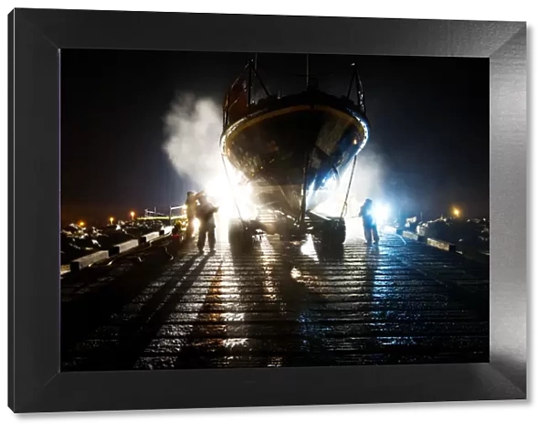 Hoylake mersey class lifeboat Lady of Hilbre 12-005 being washed down by shore crew on the slipway at night. Taken from The Lifeboat: Courage on our Coasts. Page 37