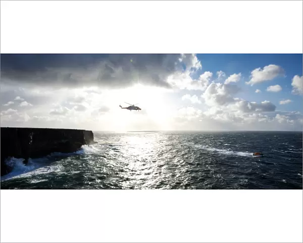 Beyond the dramatic limestone cliffs of the Aran Islands, Irish Coast Guard helicopter Rescue 115 and Severn class David Kirkaldy patrol the heaving Atlantic waters at the entrance to Galway Bay