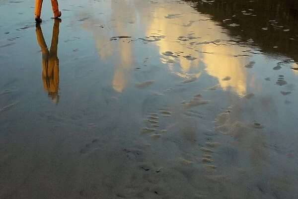 Artistic shot of a crew member walking across wet sand at Barra