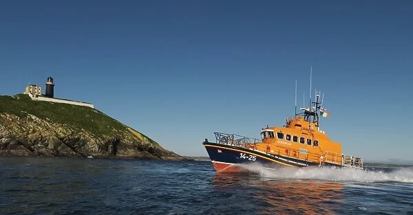Ballycotton Trent Class lifeboat Austin Lidbury 14-25 moving from right to left, lighthouse in the background. Bright sunny day, blue sky