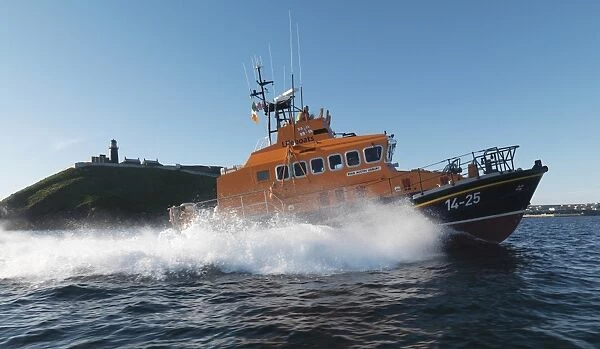 Ballycotton Trent Class lifeboat Austin Lidbury 14-25 moving from left to right, lighthouse in the background. Bright sunny day, blue sky