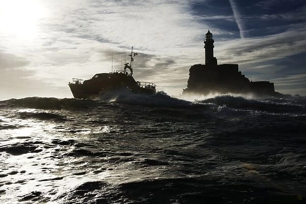 Baltimore Tamar class lifeboat Alan Massey 16-22 silhouetted against sky and Fastnet lighthouse