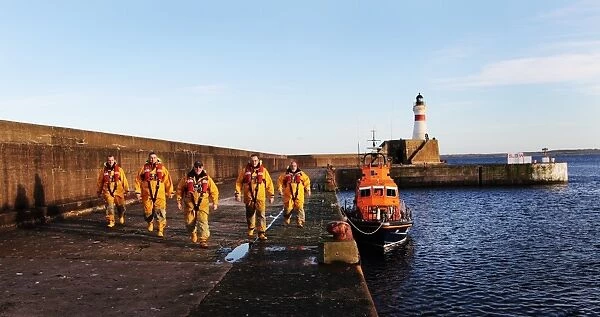 Fraserburgh crew members in full ALB kit next to the Trent class lifeboat Willie and Mary Gall 14-34 moored in the harbour