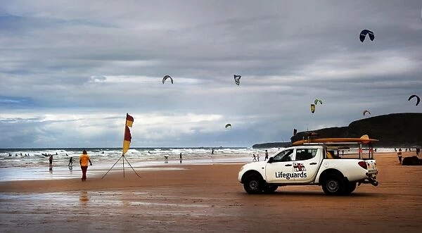 Lifeguards monitoring the beach from a patrol vehicle, lots of kites in the distance