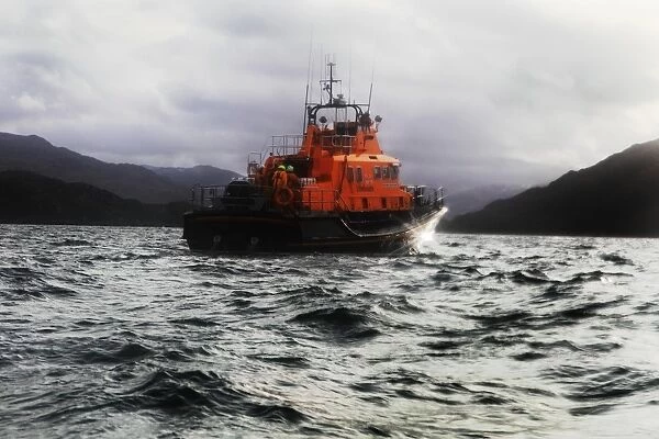 Mallaig severn class lifeboat Henry Alston Hewat 17-26. Lifeboat in the distance moving from left to right, hills and cliffs behind