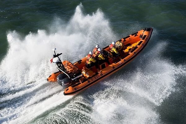 Newquay Atlantic 85 class inshore lifeboat The Gladys Mildred B-821. Lifeboat heading left to right, four crew on board, lots of white spray