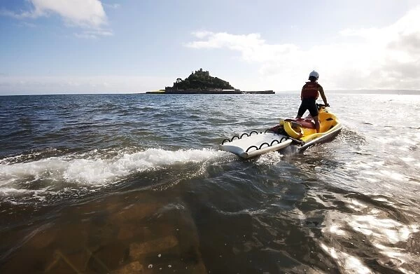 RNLI lifeguard on a rescue watercraft (RWC) with St Michaels Mount near Penzance in the background