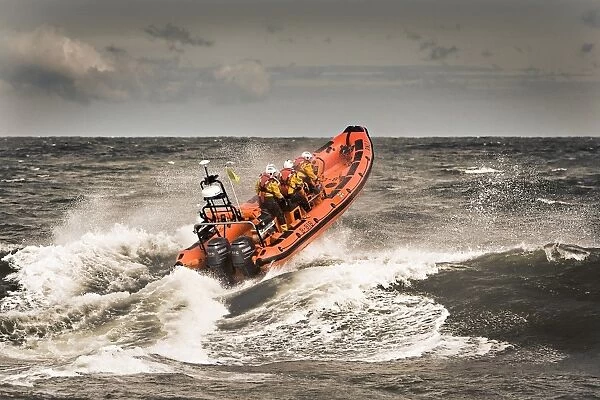 Sheringham Atlantic 85 inshore lifeboat The oddfellows B-818. Lifeboat is heading away from the camera over a breaking wave, bow high out of the water and four crew on board