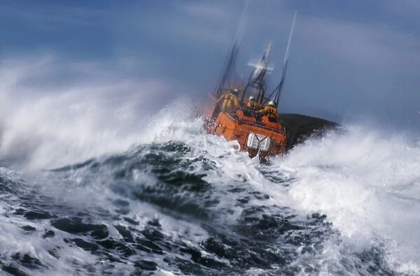 St Davids Tyne class lifeboat Garside 47-026 in rough seas. Three crew can be seen at the upper steering position. Lifeboat is partially obscured by a large wave and lots of