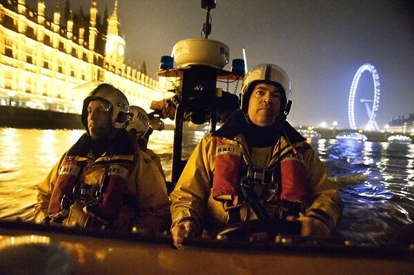 Tower lifeboat crew members on board an E-class lifeboat on the River Thames at night