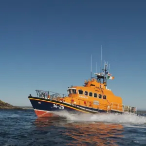 Ballycotton Trent Class lifeboat Austin Lidbury 14-25 moving from right to left, lighthouse in the background. Bright sunny day, blue sky