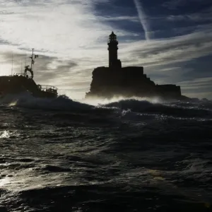 Baltimore Tamar class lifeboat Alan Massey 16-22 silhouetted against sky and Fastnet lighthouse