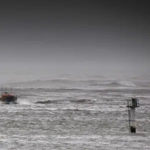 Berwick upon Tweed Mersey class lifeboat Joy and Charles Beeby 12-32 heading toward the camera in rough seas. Harbour wall and lighthouse to the left of the photo