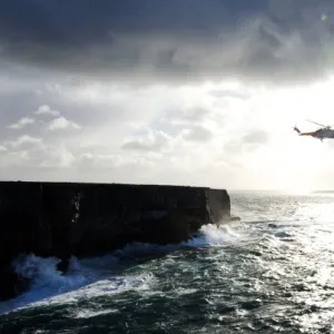 Beyond the dramatic limestone cliffs of the Aran Islands, Irish Coast Guard helicopter Rescue 115 and Severn class David Kirkaldy patrol the heaving Atlantic waters at the entrance to Galway Bay