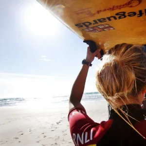 Female lifeguard lifting rescue boards down from a patrol vehicle