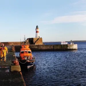 Fraserburgh crew members in full ALB kit next to the Trent class lifeboat Willie and Mary Gall 14-34 moored in the harbour