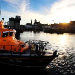 Fraserburgh Trent class lifeboat Willie and Mary Gall 14-34 in the harbour, sun low behind buildings in the background