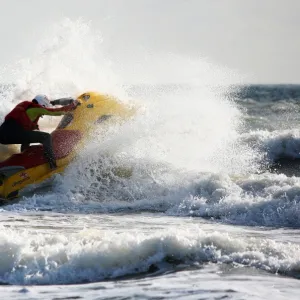 Lifeguards on Boscombe beach, Dorset. Lifeguards are now providing year round cover at Boscombe due to the development of the surf reef. Lifeguard on a rescue watercraft moving from left to right through a breaking wave