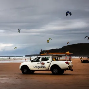 Lifeguards monitoring the beach from a patrol vehicle, lots of kites in the distance