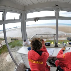 Two lifeguards monitoring the sea at a beach in Jersey from lifeguard hut