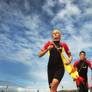 Two lifeguards running along the beach towards the camera, taken from below looking up