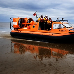 New Brighton hovercraft Hurley Spirit H-005 during a training exercise on mudflats. Four crew in view, hovercraft moving from left to right