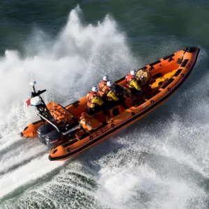 Newquay Atlantic 85 class inshore lifeboat The Gladys Mildred B-821. Lifeboat heading left to right, four crew on board, lots of white spray