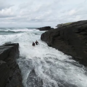 Reconstruction of the rescue of a fisherman by two RNLI lifeguards Chris Boundy and John Dugard at Trebarwith Strand, Cornwall. Picture shows the two lifeguards struggling through surf in the area called the Washing Machine, fisherman on rocks