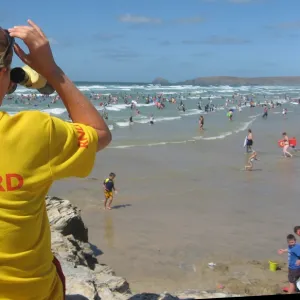 An RNLI lifeguard monitoring the busy Perranporth beach